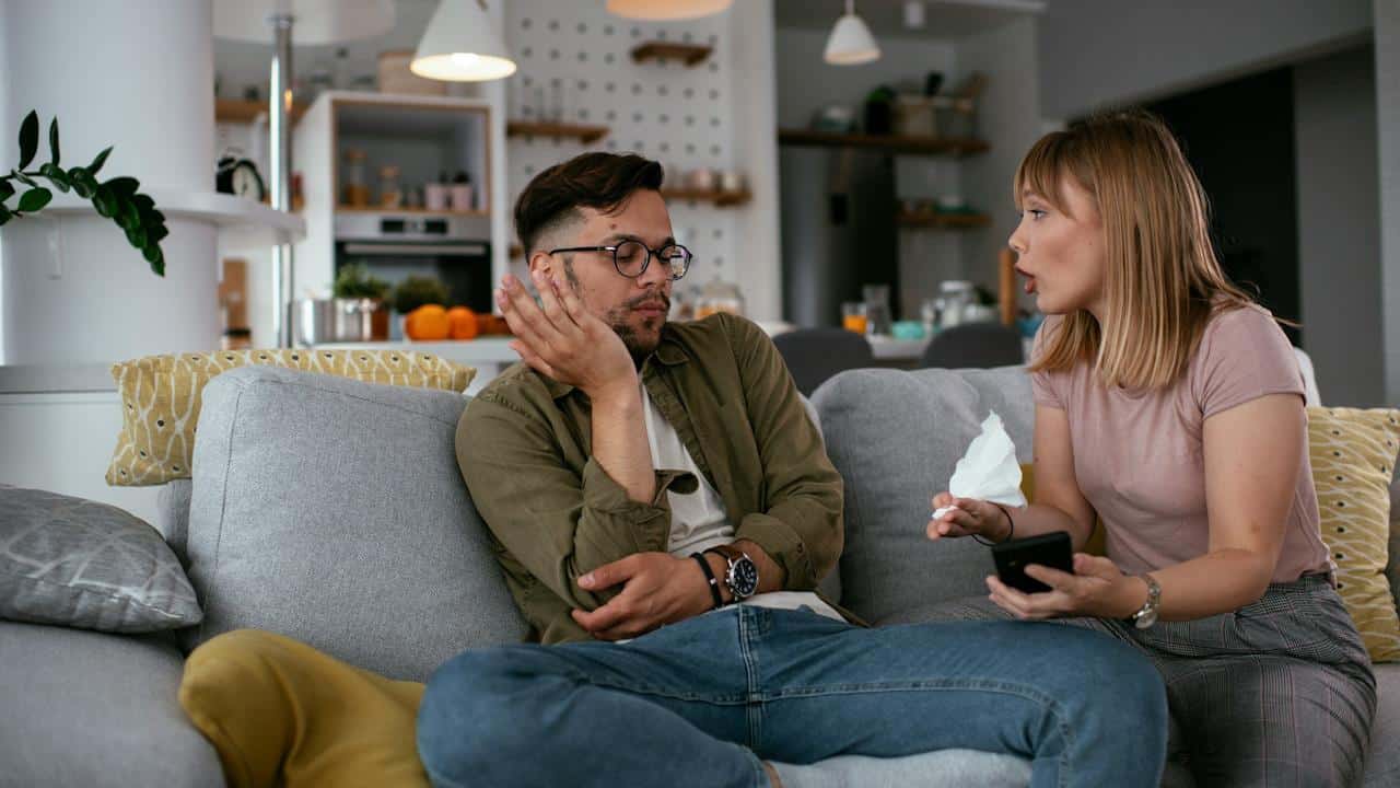 A woman yelling at her boyfriend while they are sitting together at home.
