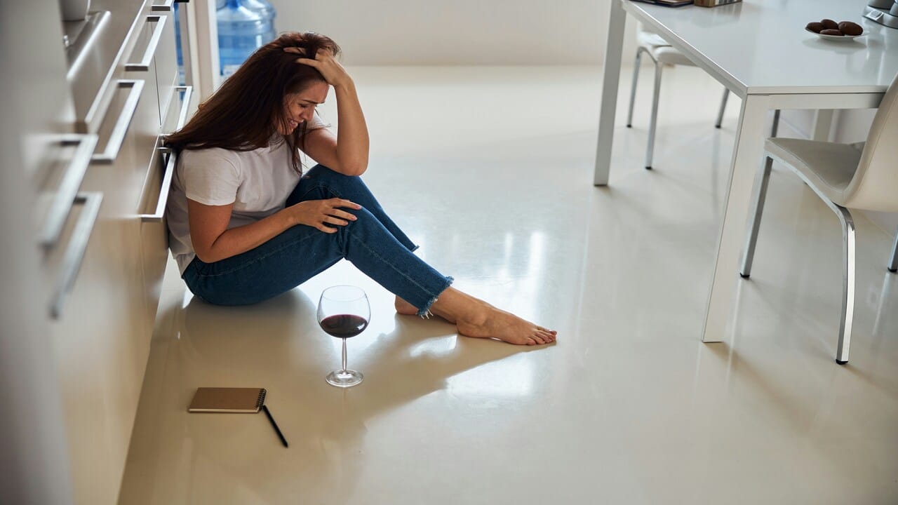 A woman drinking wine while upset