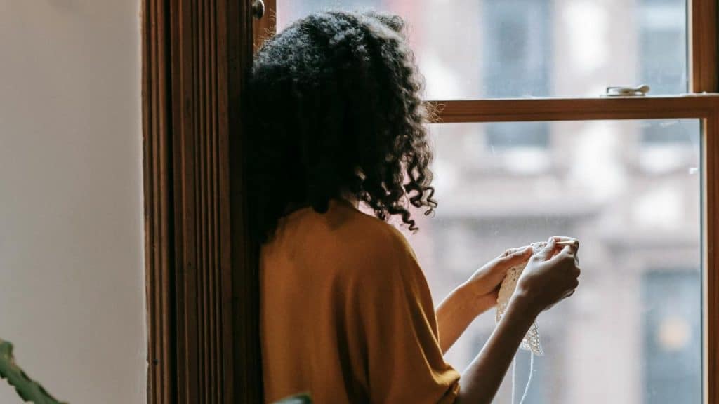 A person knitting by a window.