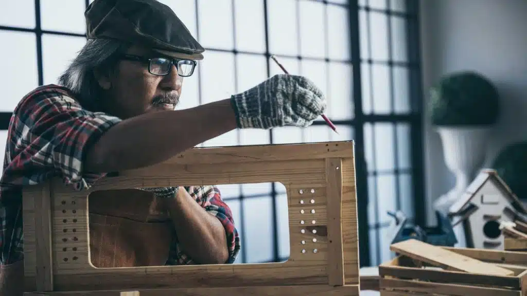A craftsman marking a wooden frame in a workshop