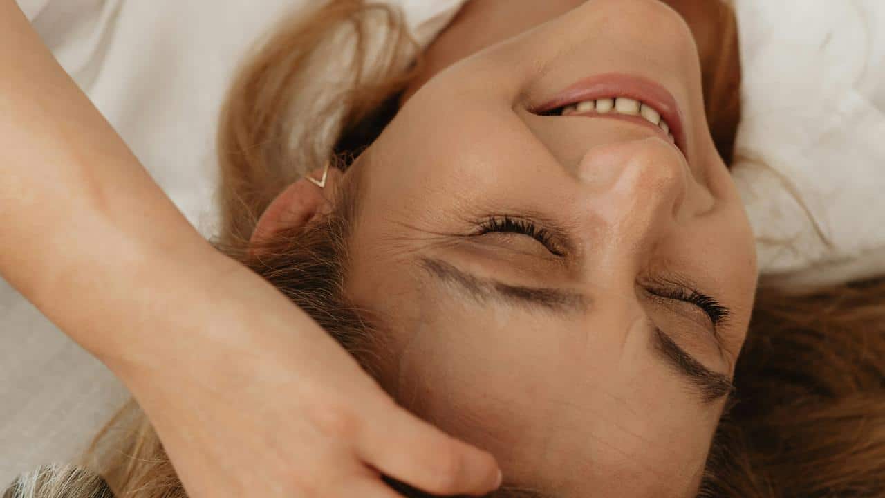 A woman smiling with her eyes closed while lying down