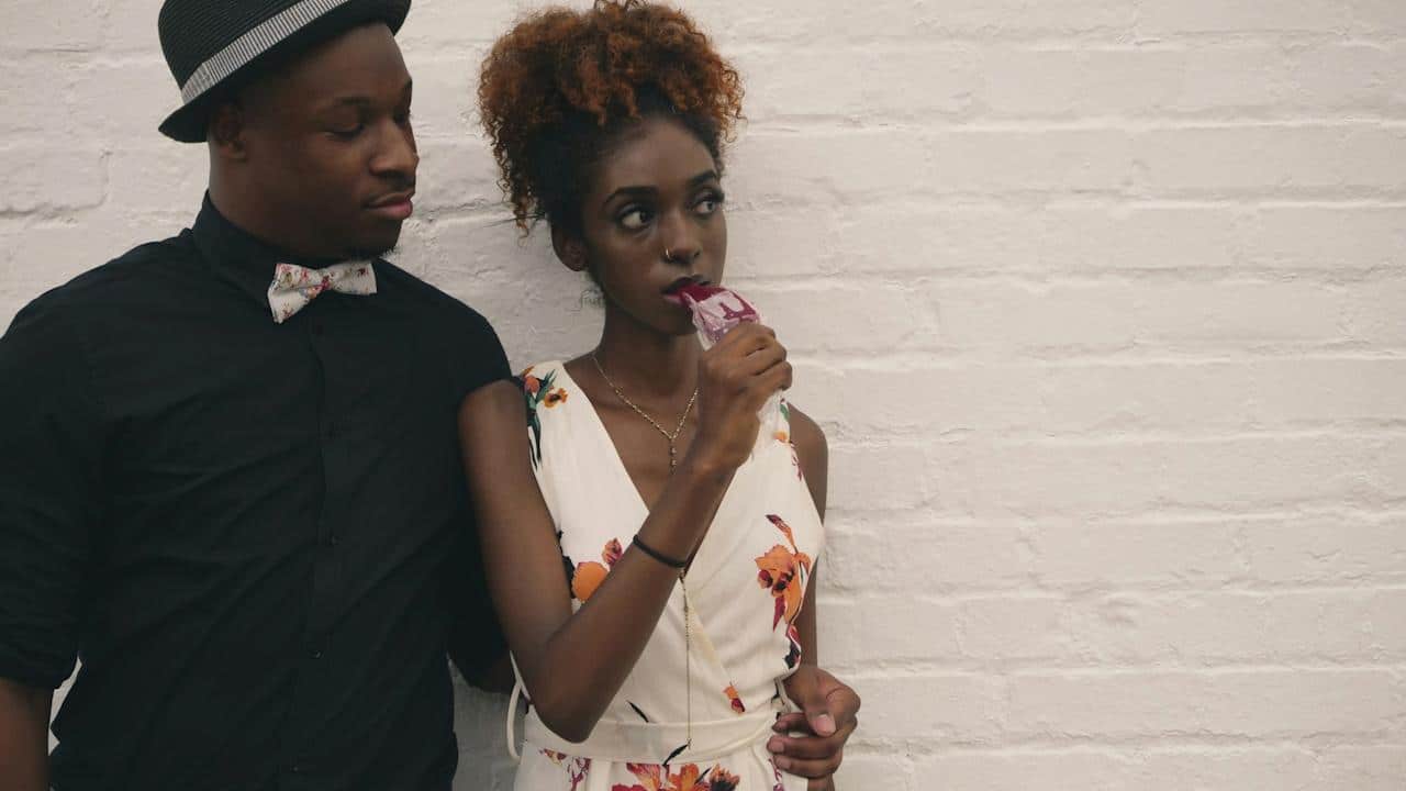 A man and a woman standing in front of a white-painted wall.