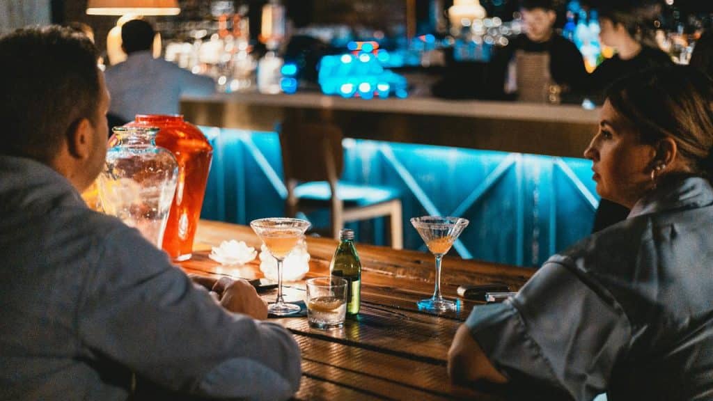 A couple sitting at a bar with cocktails