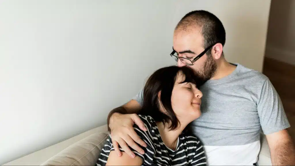 A man kissing woman’s head