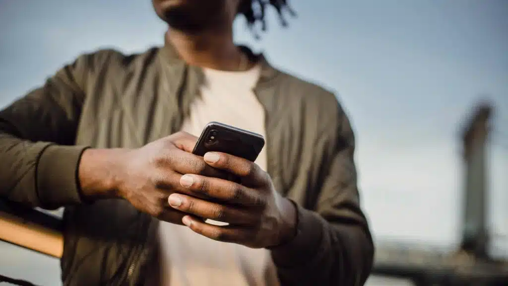 A man holding and using a smartphone outdoors.