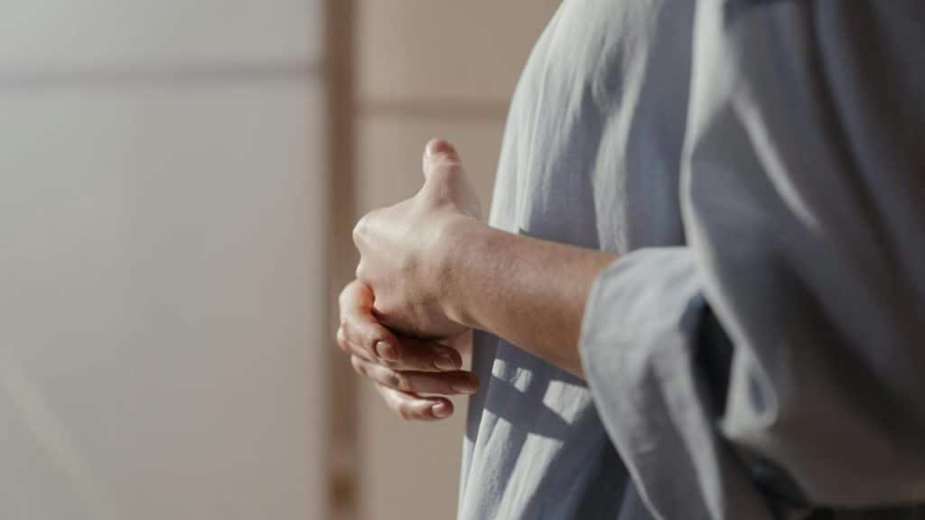 A person gently holding their wrist while standing indoors.