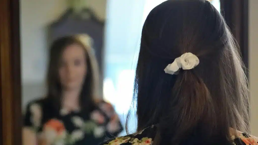 A woman looking at her reflection in the mirror.