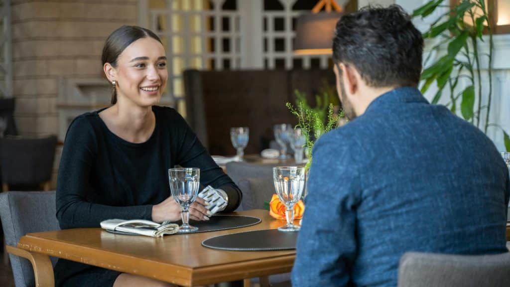 A woman smiles while sitting across from a man at a restaurant table.