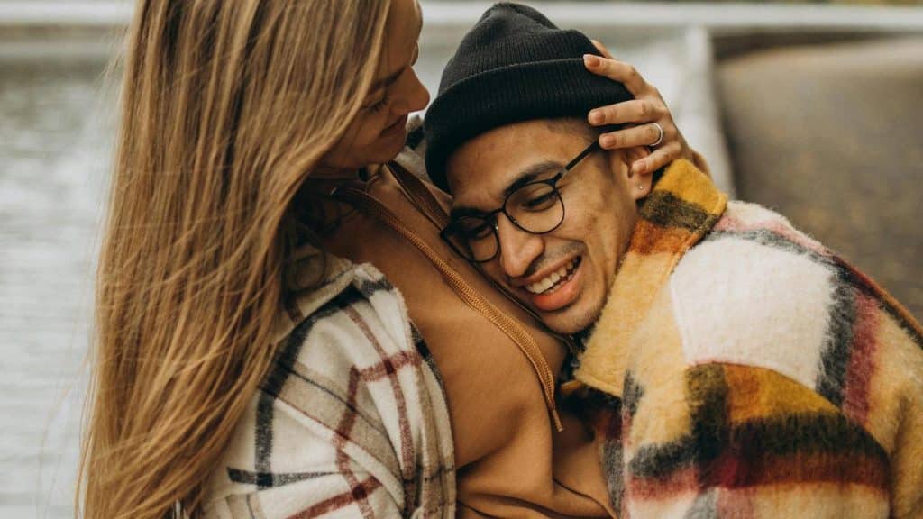 A couple sharing a warm embrace while sitting outdoors.
