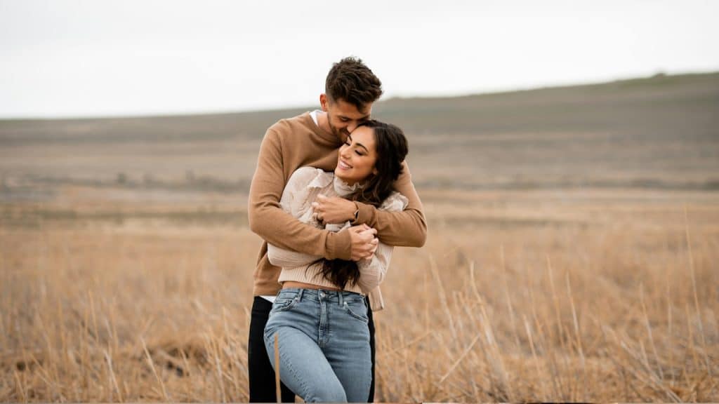 A man and a woman hugging in a field.