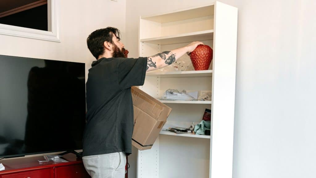 A man assembles a bookshelf in his living room.