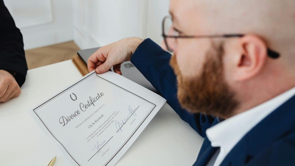 A man in a blue suit holds a document labeled as a divorce certificate.
