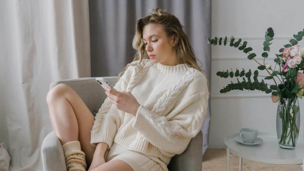 A woman sitting in a chair looking at her phone.