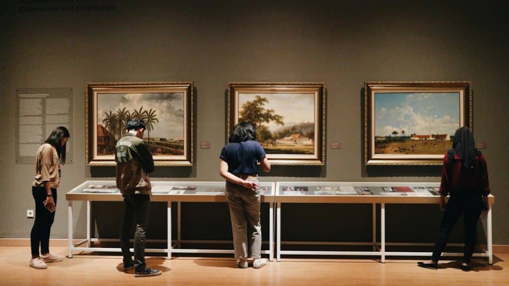 A group of people looking at paintings in a museum.