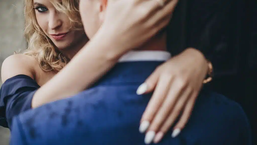 A blonde woman rests her hand on the shoulder of a person wearing a blazer.