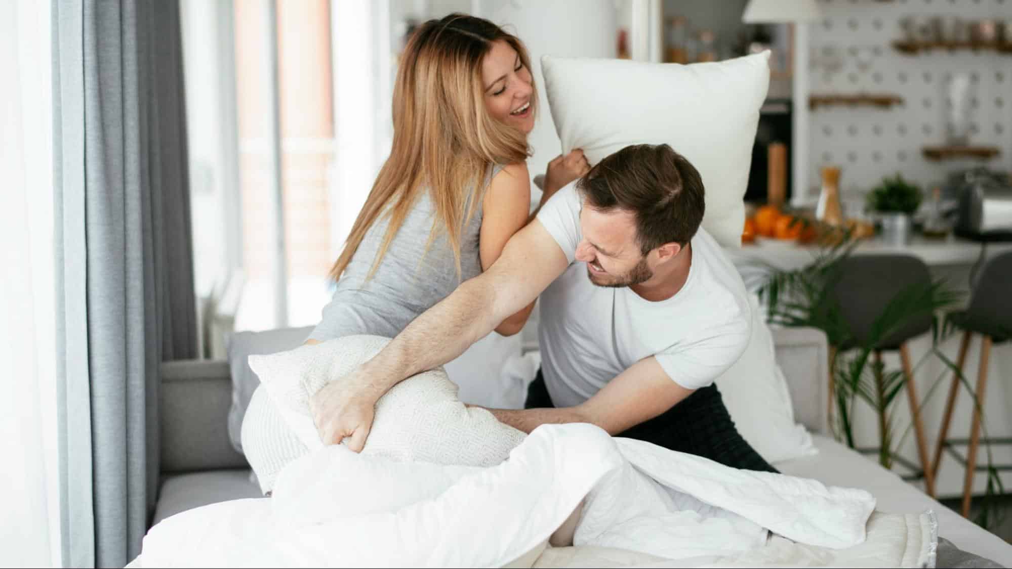 A man and woman pillow fighting