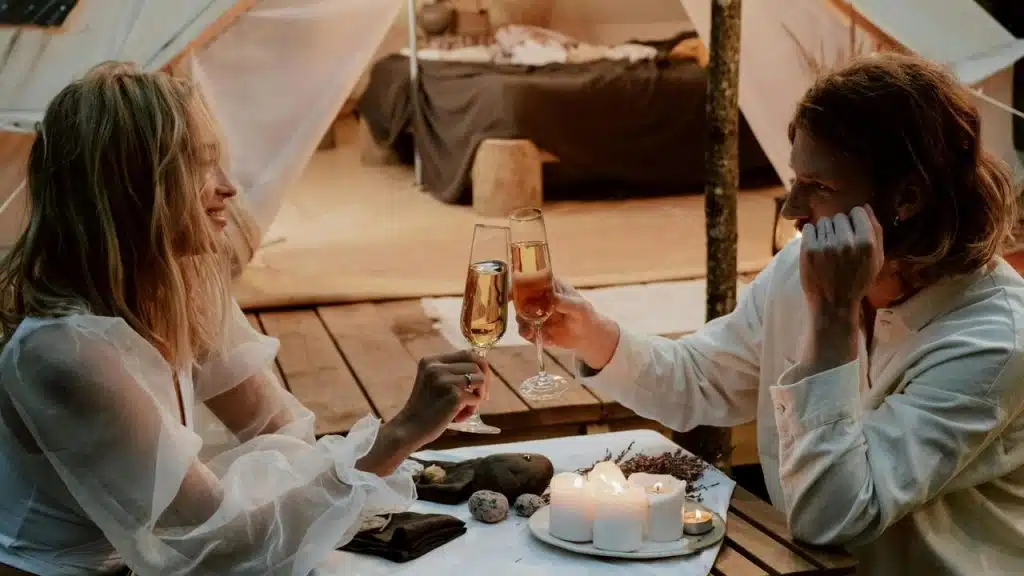 A couple toasting with champagne glasses at a candlelit dinner.