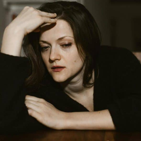 A worried woman resting her head on her hand at a table.