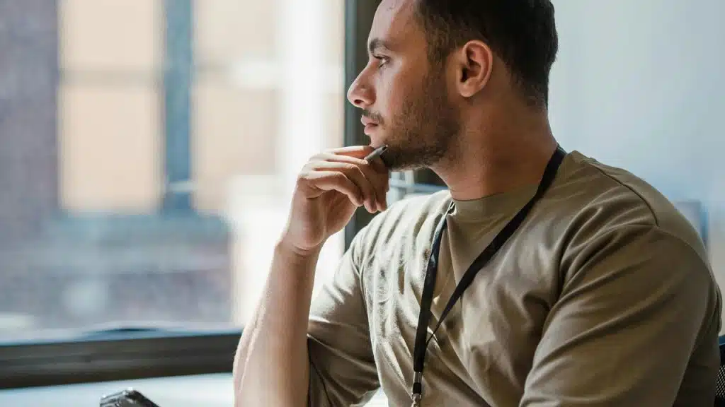 A man sitting by a window looking thoughtful.
