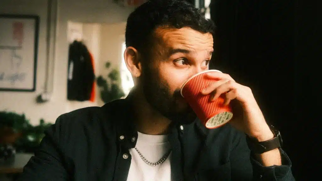 A man drinking from a red paper cup