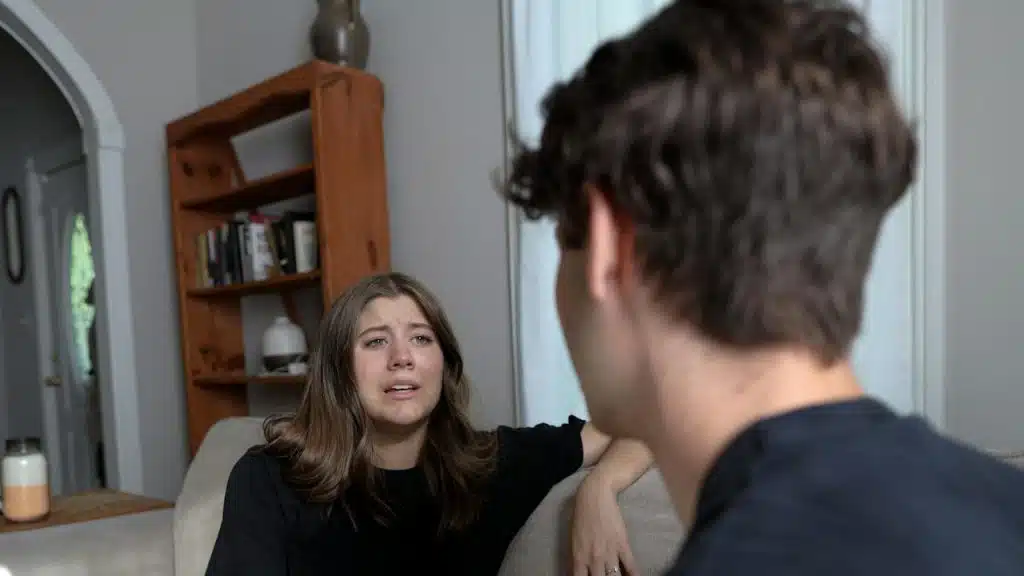 A woman complaining to her husband while sitting at a couch indoors