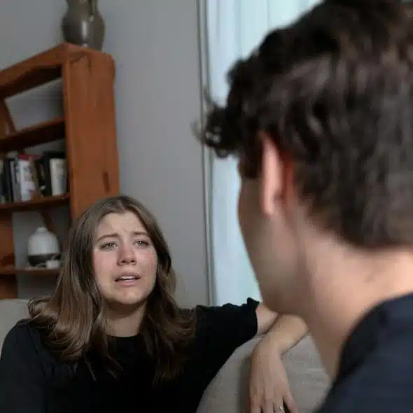 A woman complaining to her husband while sitting at a couch indoors