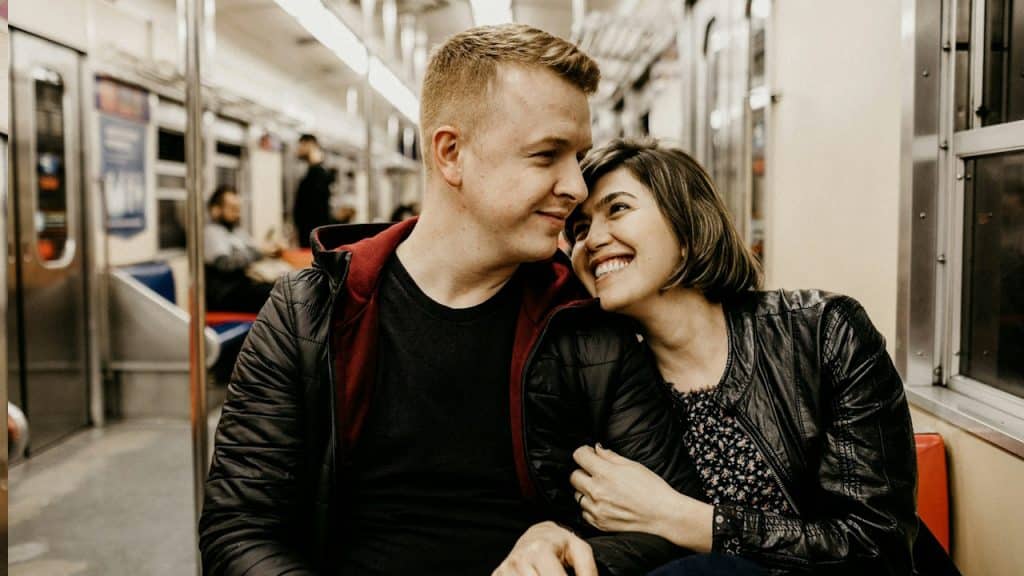 A woman hugging a man while sitting inside a train.
