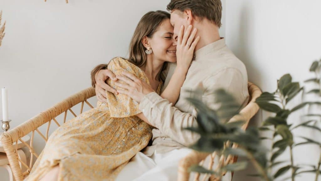 A couple embracing affectionately in a wicker chair.