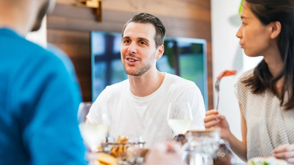 A man talking with friends at a dining table.