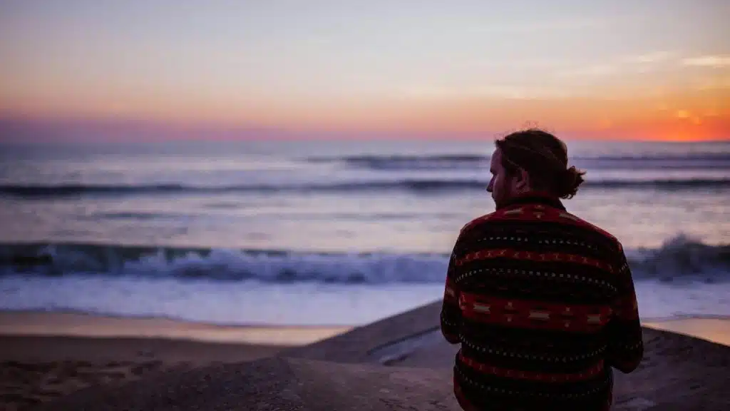 A person sitting on the beach watching the ocean at sunset.