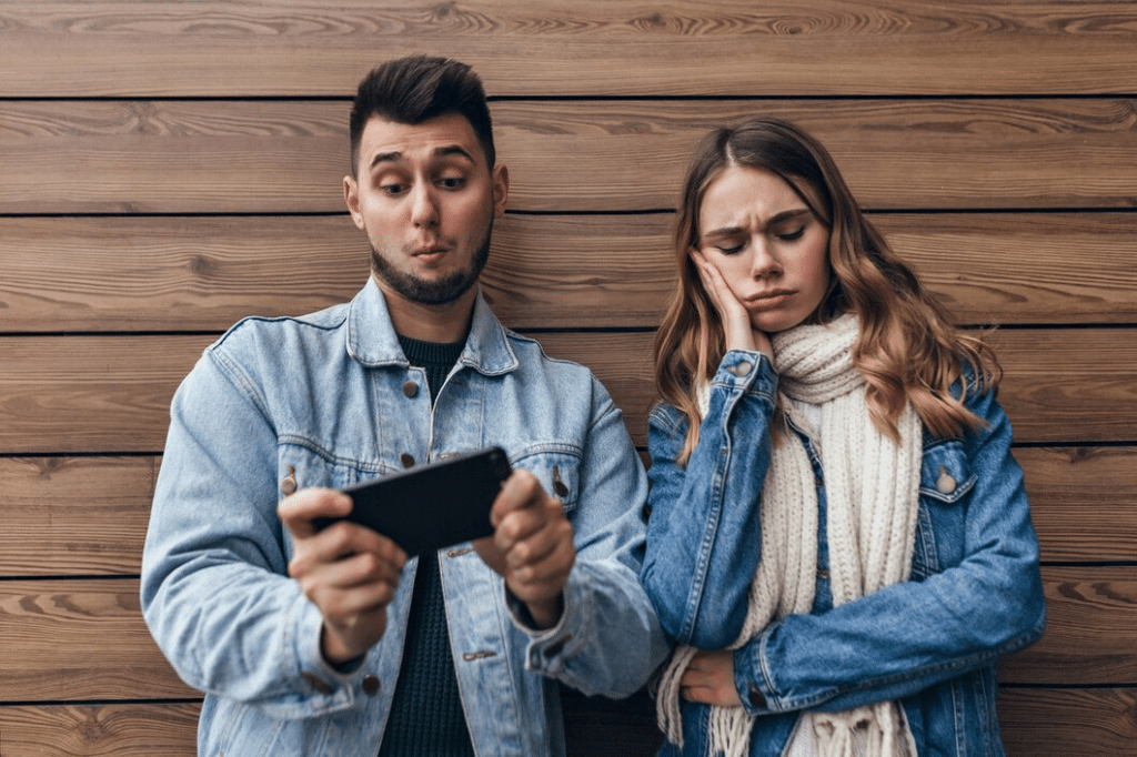Man checking his phone while his girlfriend is distressed