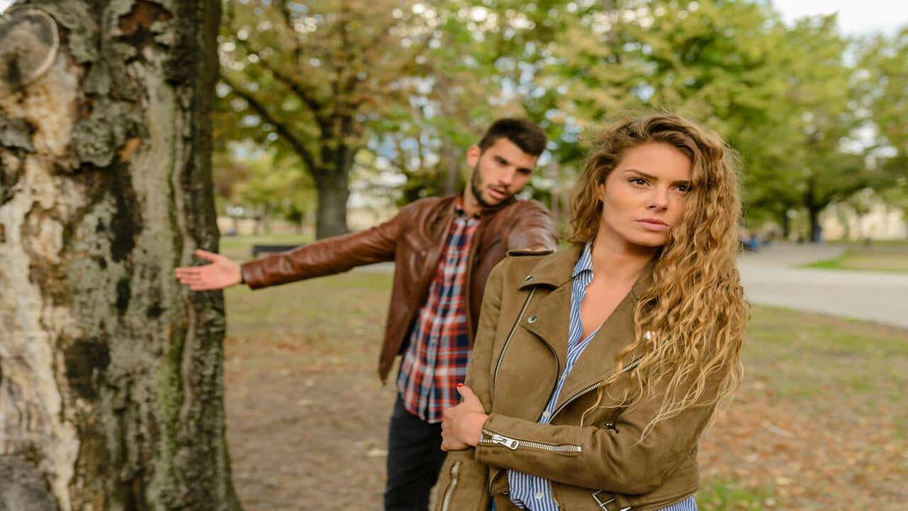 A couple fighting by a tree