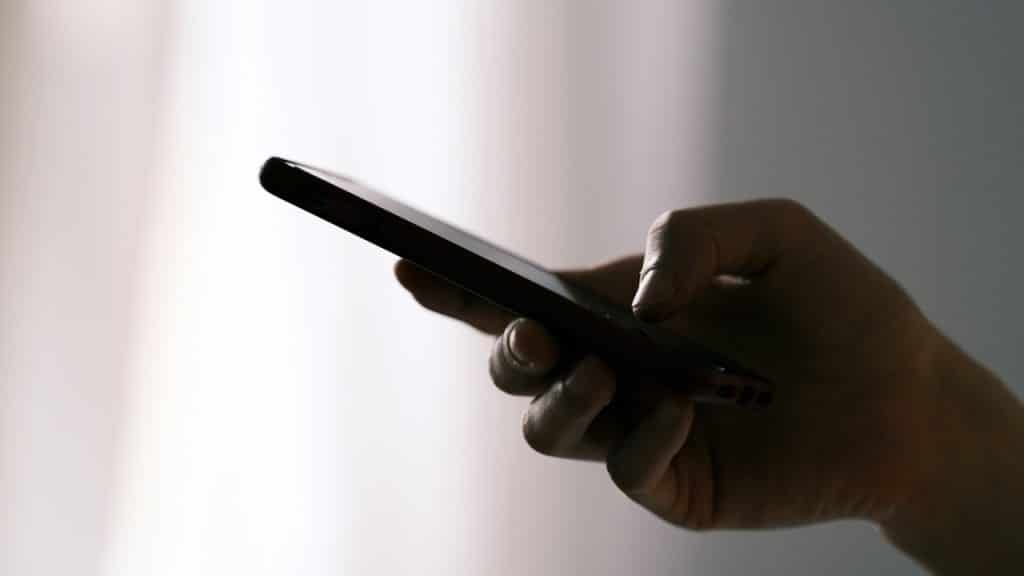 A person holding a smartphone in a dimly lit setting.