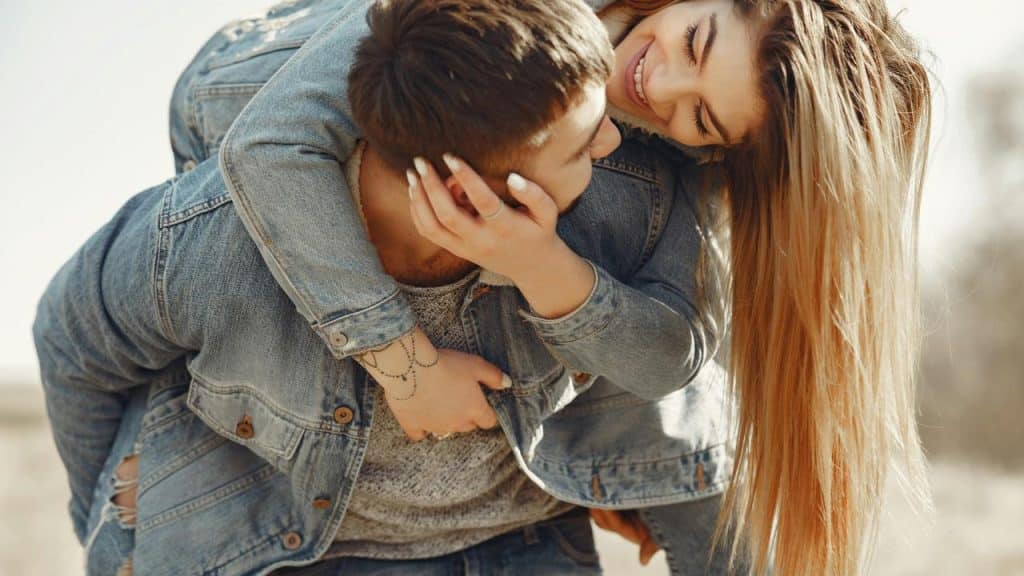 A woman smiling while riding piggyback on a man