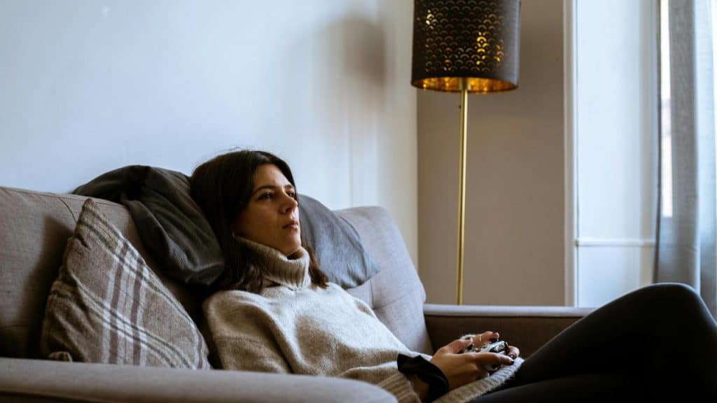 A woman relaxing on a couch holding a game controller.