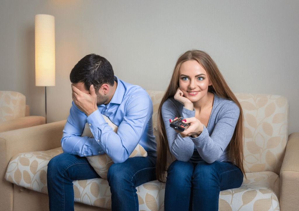 Portrait of couple sitting on sofa watching television