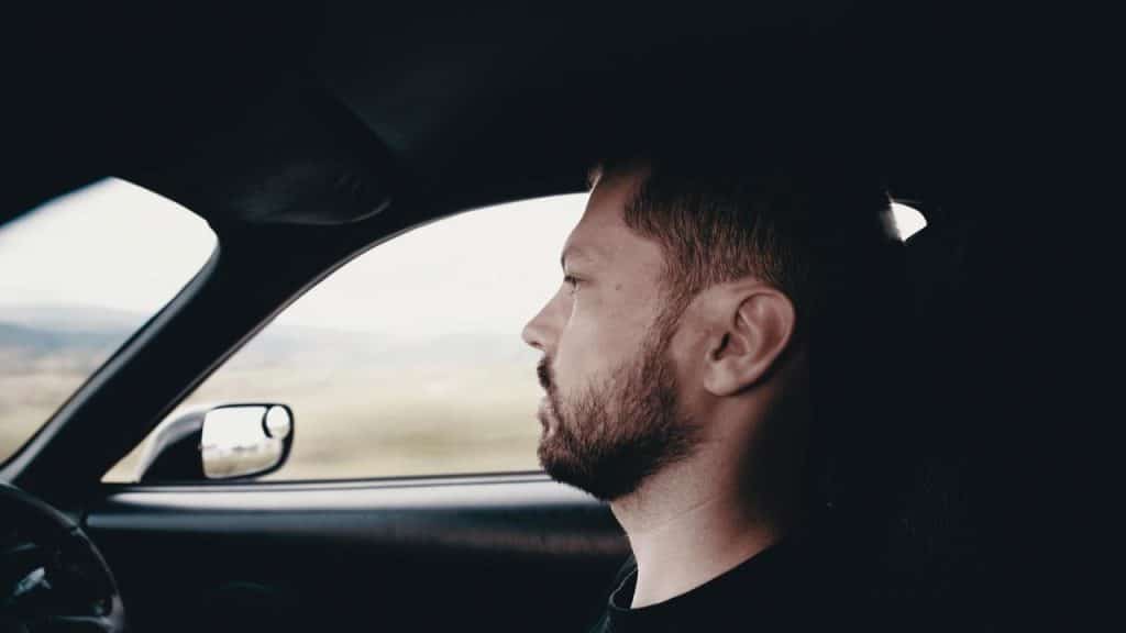 A man driving a car and looking focused on the road ahead.