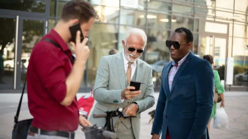 Three men stand together outdoors, with one man talking on his smartphone.