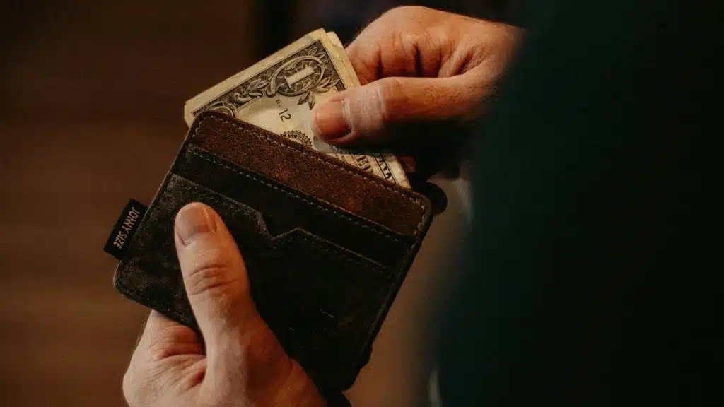 A man holding a wallet and taking some money out of it.