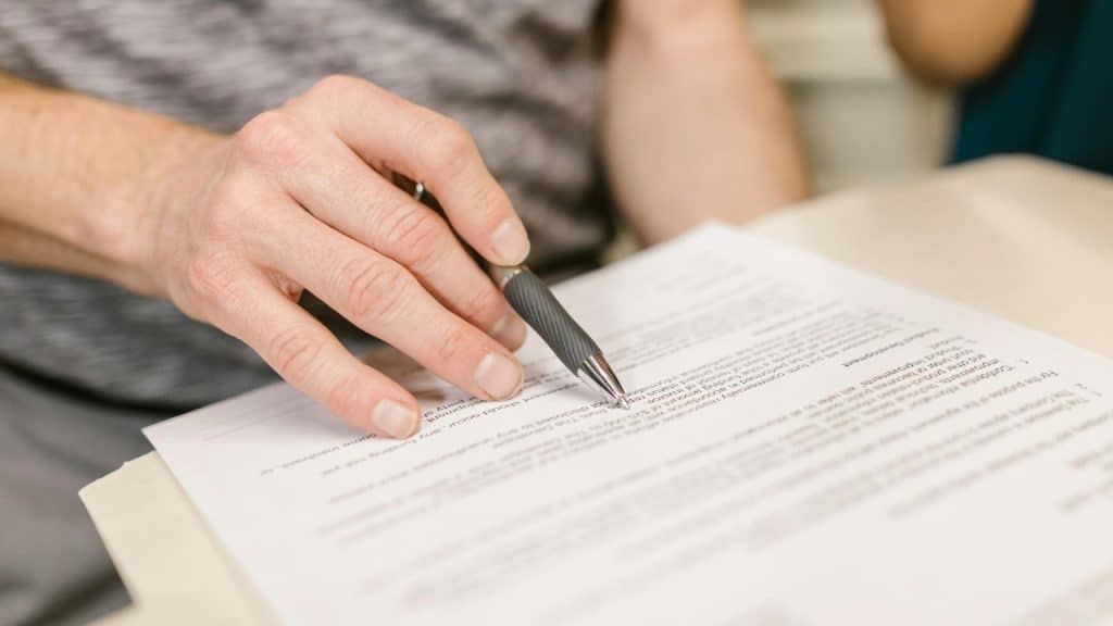 A close-up view of a person using a pen to review a printed document.