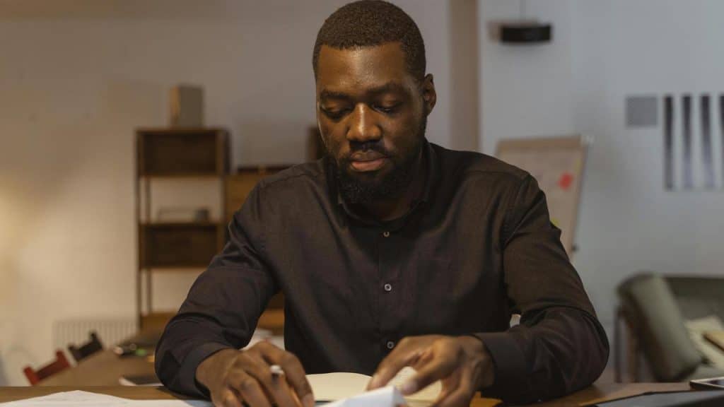 A man sitting at a desk and reading documents in an office.