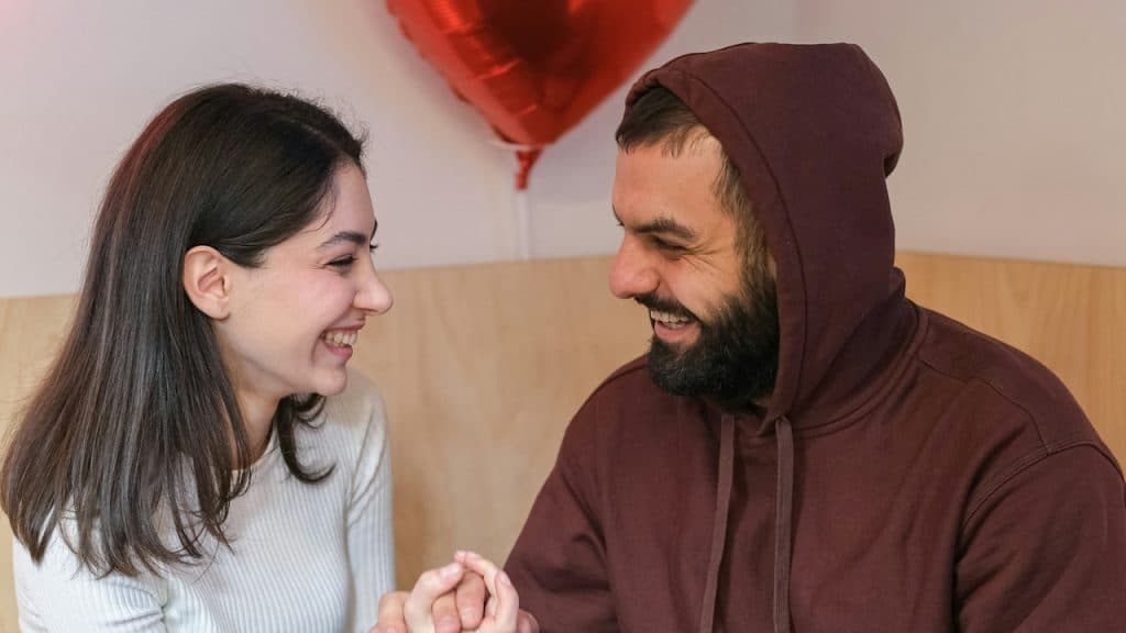 A man and a woman holding hands while sitting together in a restaurant.