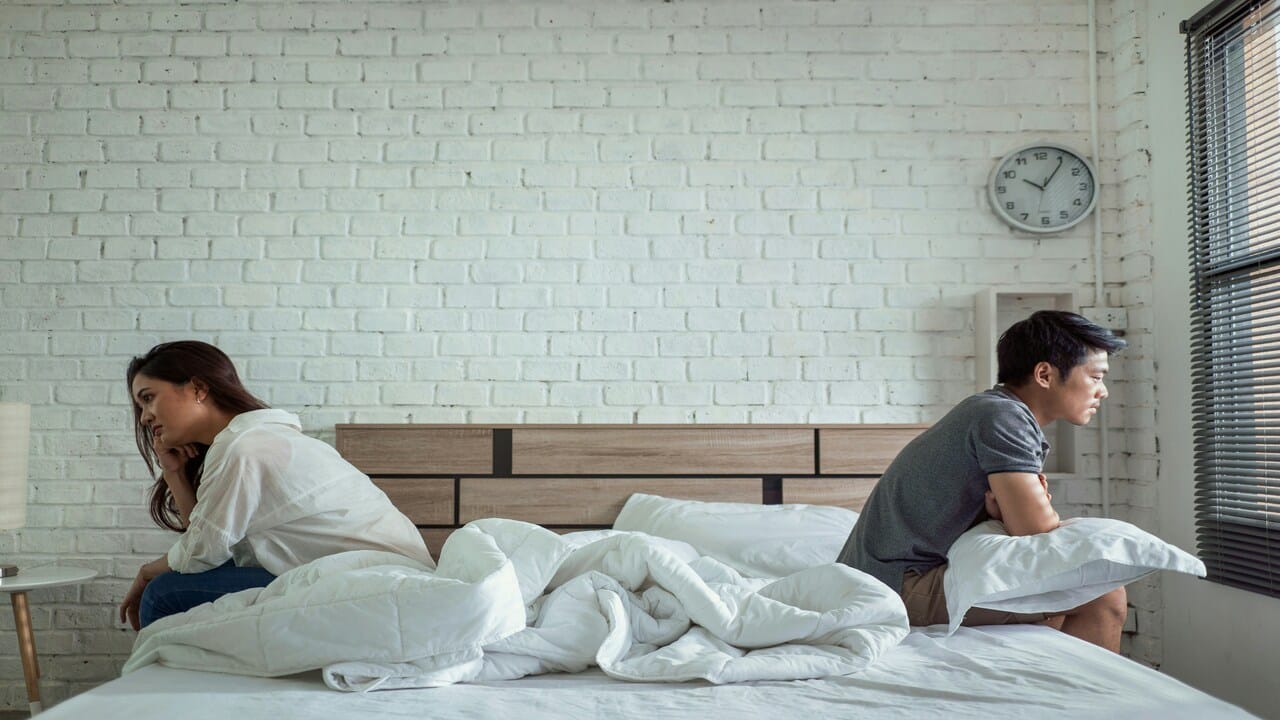 A couple not looking at each other while in bed