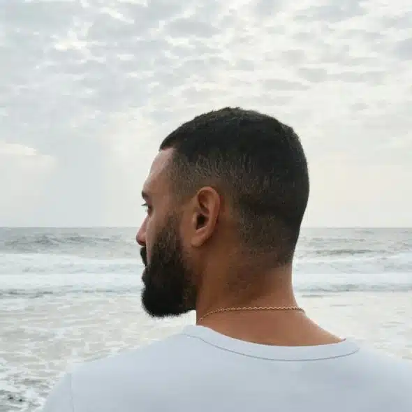 A man standing on the beach looking at the ocean.