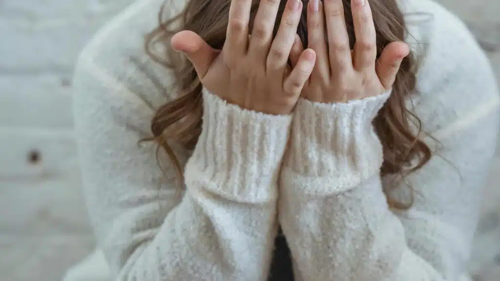 A woman covering her face with her hands, appearing distressed or upset.