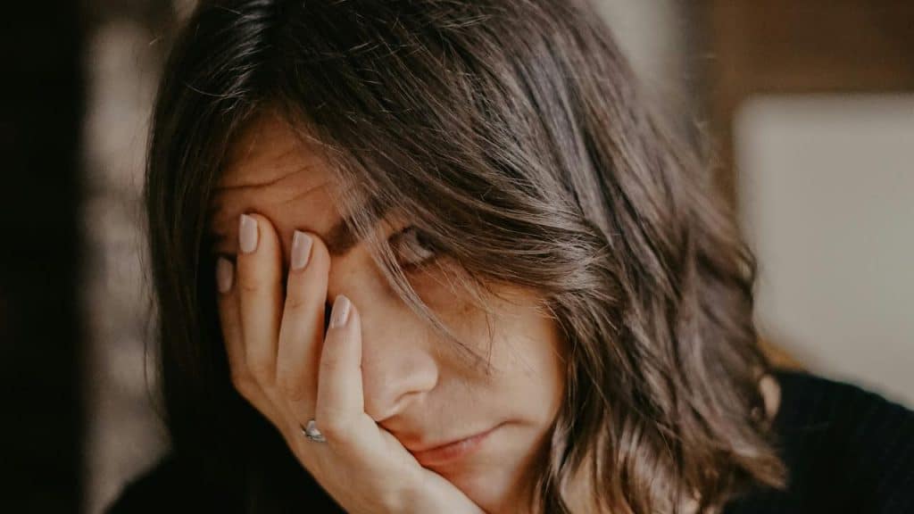 A woman covering her face with her hand, appearing tired or stressed.