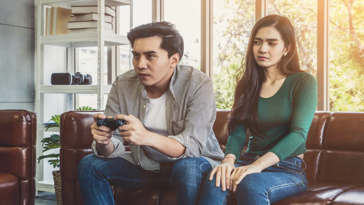 A man ignoring his wife to play a video game