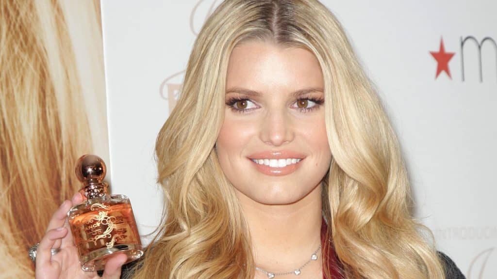 A photo of Jessica Simpson holding a perfume bottle and smiling.