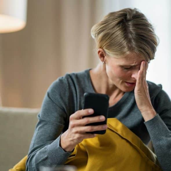 Woman crying while holding a phone