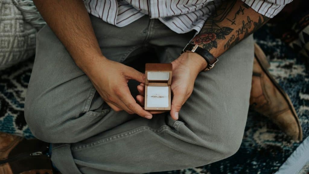 man sitting thoughtfully while holding a ring box